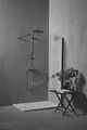 Duschsystem von Ideal Standard mit mattgrauem Finish, klarer Glasabtrennung, Wandmontage und flat formatierten Ablagen für Handtücher und Pflegeprodukte.